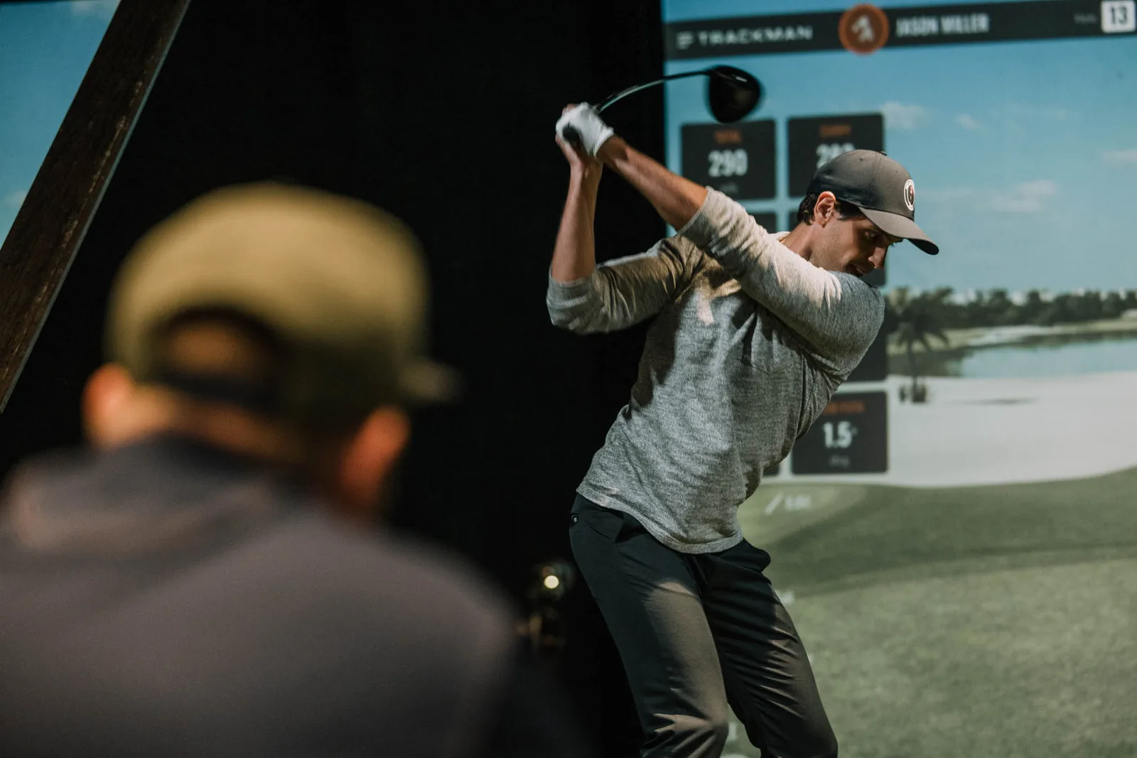 Golfer at the top of the backswing in a Trackman simulator bay