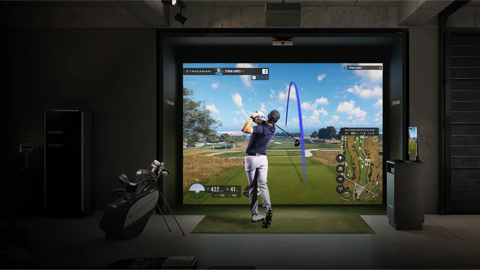 Golfer hitting a shot in a Trackman simulator bay with the ball flight traced on screen